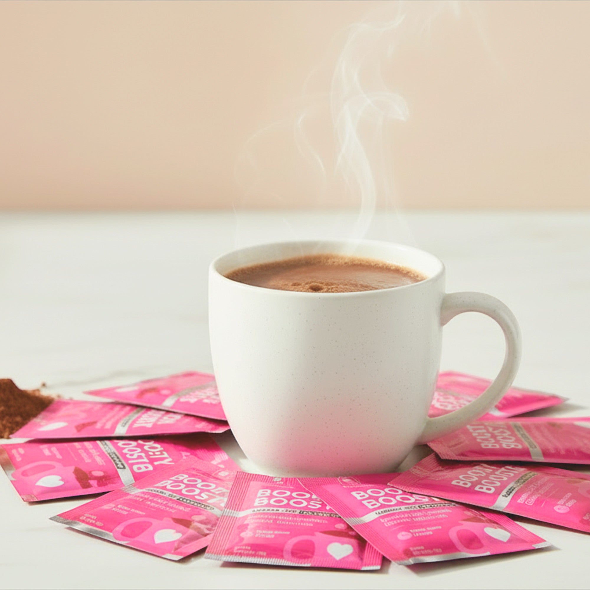 Ninja Mama Booby Booster organic lactation chocolate drink in a white mug, surrounded by pink sachets.